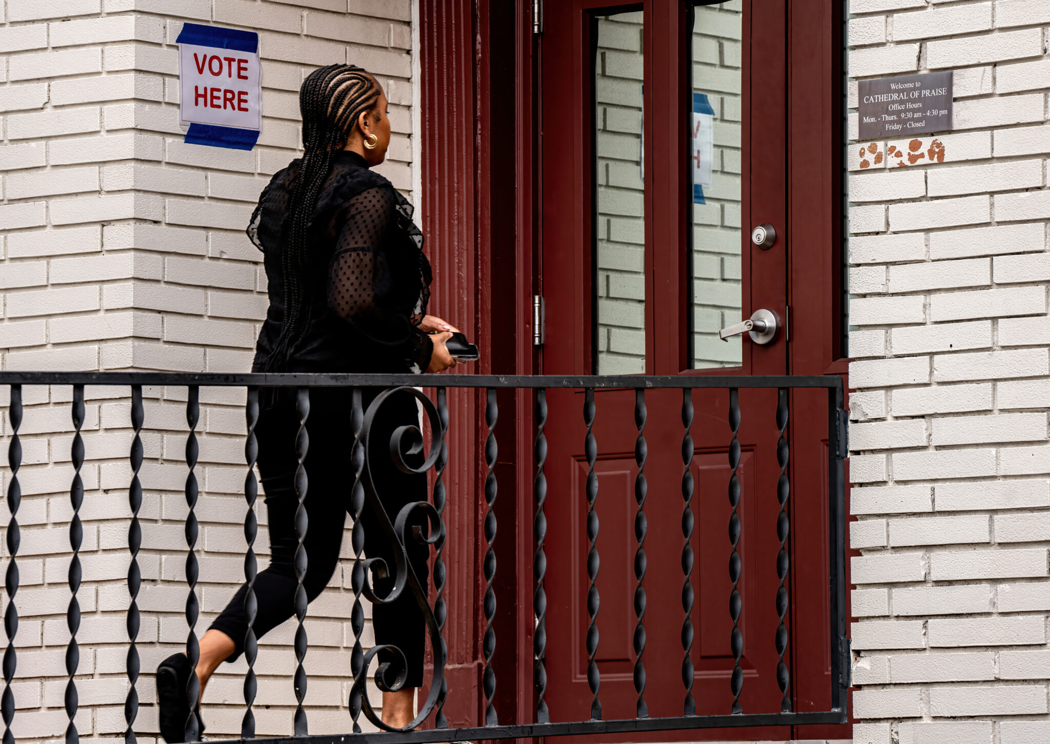 A person approaches an entrance beside a Vote Here sign.
