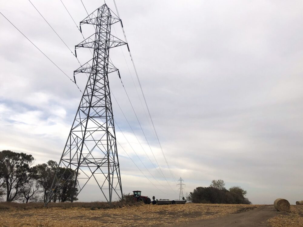 Electricity transmission towers and power lines across an open landscape.